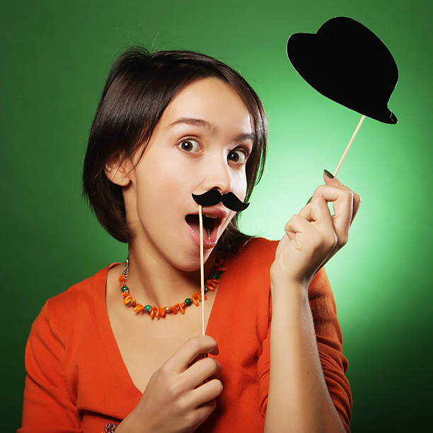 A young girl wearing sunglasses poses against a yellow background, gesturing with both hands.