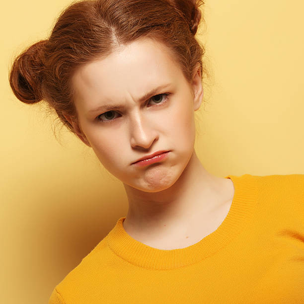 frowning young redhair woman thinking on yellow background