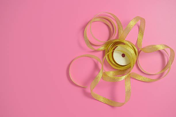 One small gold colored decorative gift bow isolated on white background with Copy Space, symbolizing holiday presents and festive packaging.