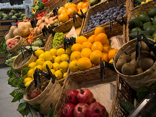 Various fruits are neatly arranged in baskets at a bustling market, showcasing bright colors