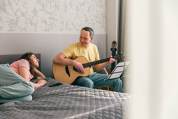 istock Man playing acoustic guitar while partner listens in bedroom 2252469837