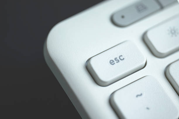Fingers hover over the escape key on a keyboard