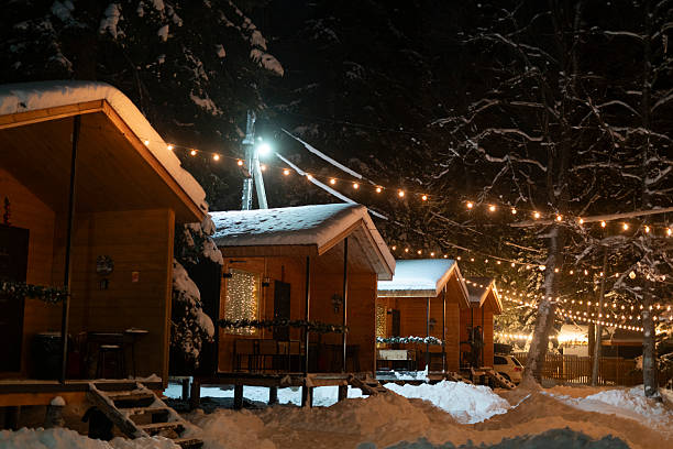 istock Small cabins sit in snow at night, lit by string lights around the area creating a warm atmosphere 2252478322