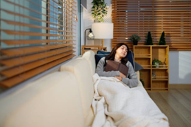 istock Pretty young woman falling sleep while reading a book sitting on sofa at home 2252479330