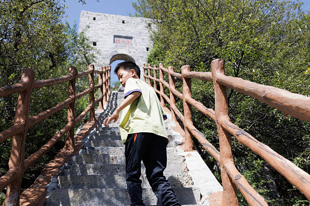 A Chinese little boy is climbing the mountain along the steps