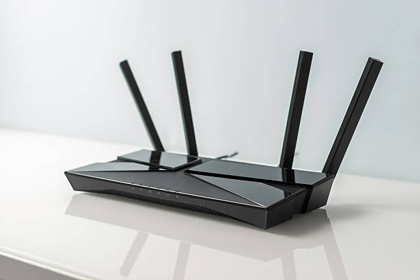 istock Black WiFi router with four antennas on glossy white desk, minimal clean workspace interior symbol of fast reliable wireless internet 2252484193