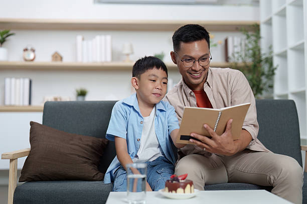 istock Family Life: Father reading a book to his son at home 2252484884