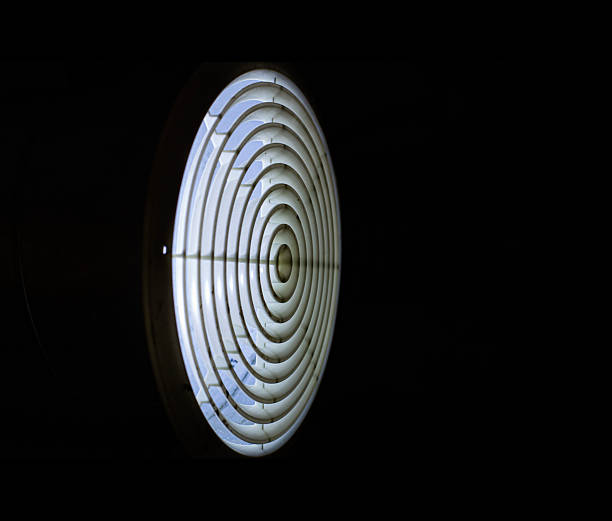 istock A close-up, architectural shot of a circular air vent on a white ceiling, showing concentric circles leading to a central point. The design highlights ventilation and climate control systems. 2252488435