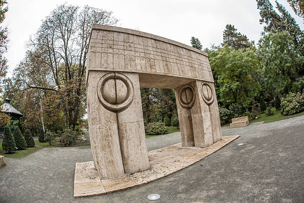 This image presents a series of spherical stone bollards arranged in a pattern on a paved pathway. Each bollard is mounted on a short cylindrical pedestal and exhibits a mottled pattern of light and dark gray, suggesting a granite composition. The bollards are positioned at regular intervals, likely serving both a decorative and functional purpose by demarcating the walkway and preventing vehicle access. The background features a brick wall, providing a contrasting texture to the smoothness of the stone spheres. This setting could be part of an urban landscape, a public garden, or the entrance to a historic building, where such bollards are often used to enhance security and aesthetics.