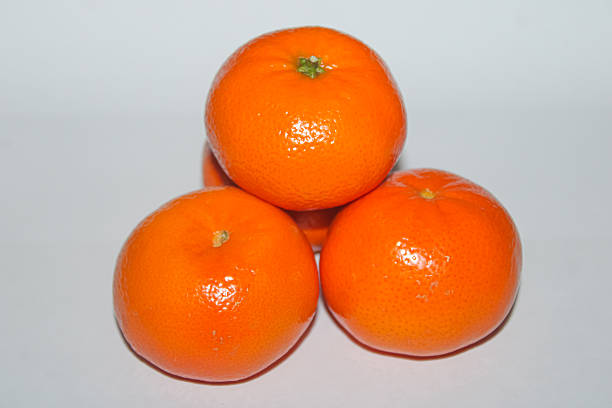 A high-quality studio shot of three ripe, juicy mandarin oranges arranged in a stable pyramid stack against a clean white background. Each citrus fruit features a bright orange, textured peel that reflects a healthy, glossy sheen. This minimalist and professional composition is perfect for health and wellness content, nutritional blogs, fruit packaging, and grocery marketing. Its clear isolation and high-resolution detail make it an essential asset for designers requiring fresh, organic produce imagery for commercial, editorial, or lifestyle projects focusing on Vitamin C and natural snacks.