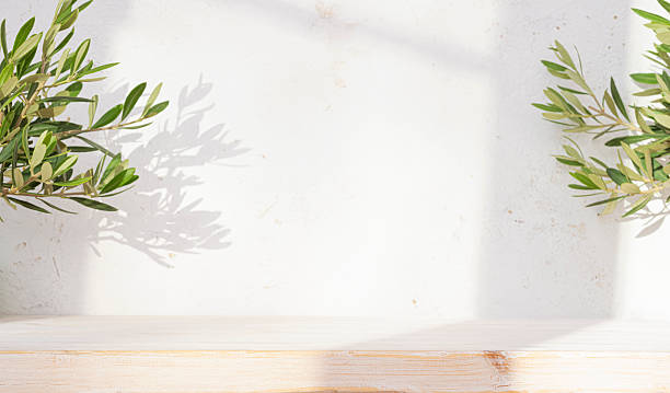 istock Background for product montage with bleached wooden table in dappled light shadows from window and tropical plant branches on abstract wall 2252491092