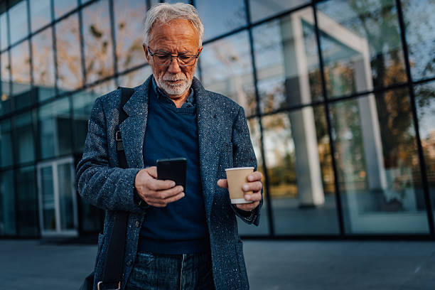 istock Senior businessman checking smartphone with coffee 2252491960