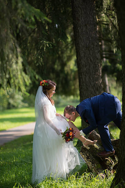 istock Groom kissing bride foot among forest trees 2252493220