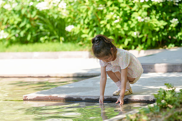 Adorable child splashing and having fun in natural spring water on hillside.