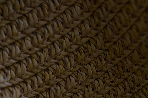 Golden Weave Texture: Close-up of Natural Raffia Braid in Concentric and Diagonal Patterns, Highlighting Organic Fiber and Artisanal Craft.