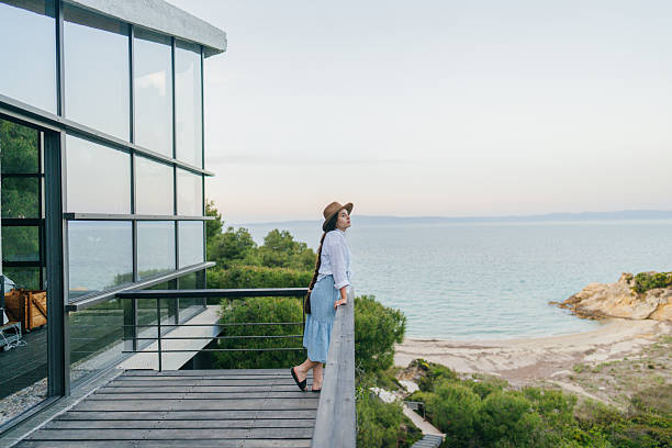 Photo of a young woman having a relaxing evening on the terrace of her home, overlooking the sea