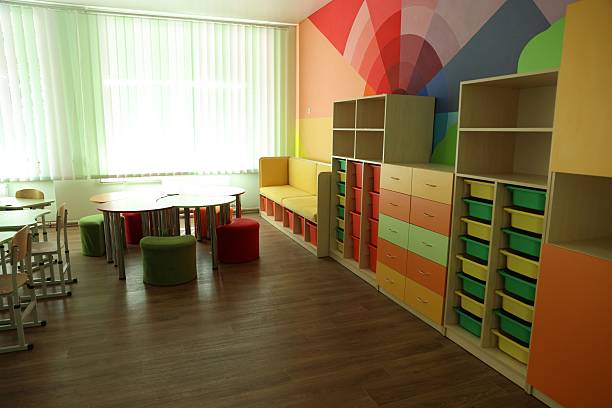istock Desks, chairs and shelving unit near bright wall in classroom 2252503671