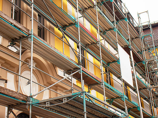 istock Building facade under renovation with metal scaffolding and protective platforms. 2252503970