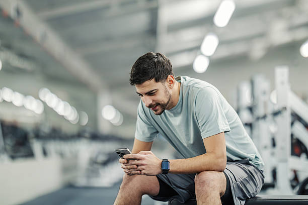 istock Young adult man checking smartphone during gym workout break 2252508586
