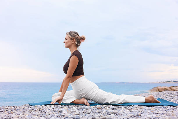 istock Young woman practicing yoga on mat at beach 2252510797