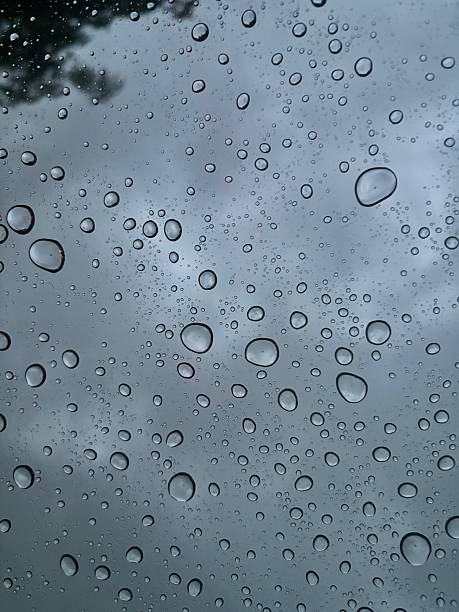 Water droplets on window during rainy weather with muted sky tones. Simple and natural background suitable for weather, nature, and atmospheric design concepts.