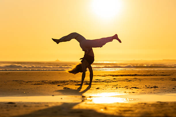 istock Woman doing handstand on beach during golden sunset 2252517899