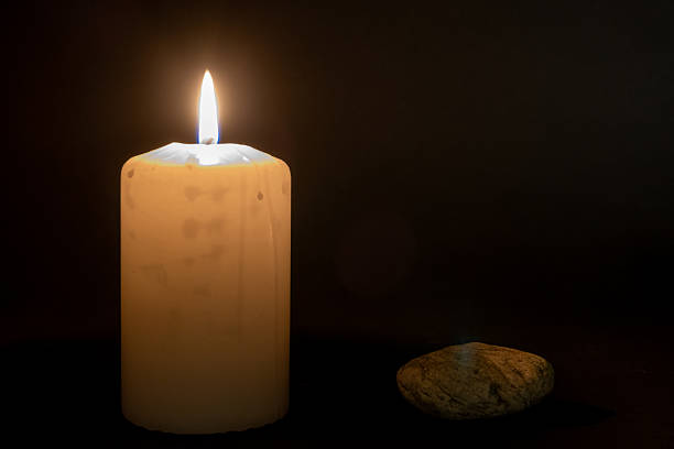 Holocaust memorial candle in darknes with stone