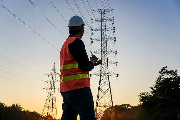 istock Adult Asian Male Electrical Engineer Using Digital Tablet to Inspect High Voltage Power Lines and Pylons at Sunset in Asia 2252524498
