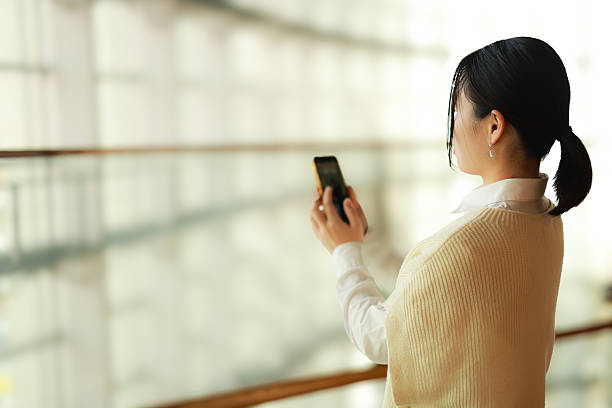 istock Beautiful young woman using mobile phone at escalater 2252524660