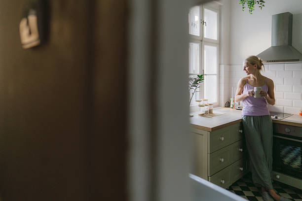 istock Young woman drinking tea in her kitchen 2252526163