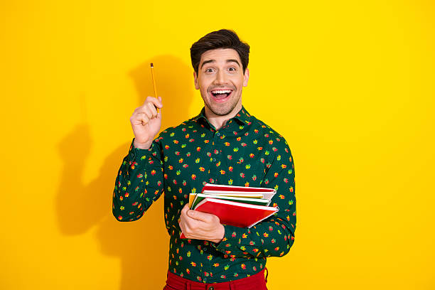 istock Cheerful young man with notebooks posing against bright yellow background ready for study and shopping 2252532829