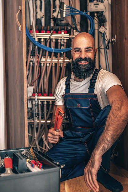 A skilled handyman works diligently on a complex utility system, inspecting pipes and connections to ensure proper function and safety