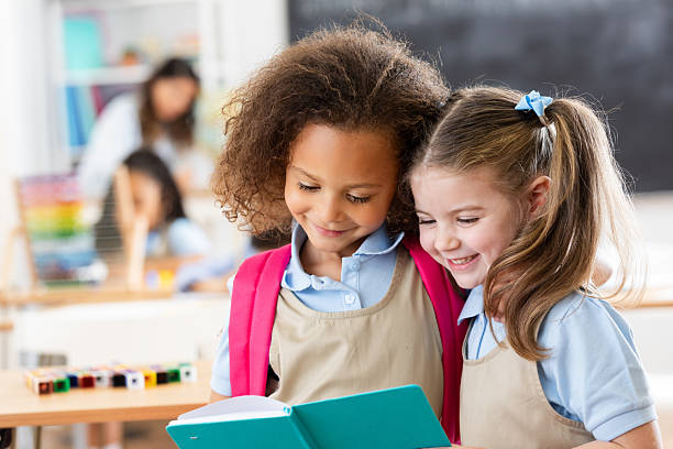 istock Diverse young students engrossed in a book, learning together in a warm classroom environment. 2252536677