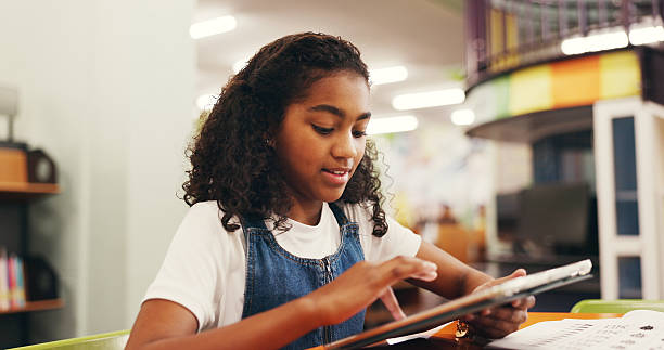istock Education, scrolling or child in library with tablet, elearning or online guide for academic development. Digital, browse and girl at table with tech, homework app or guidance in remote learning. 2252537902