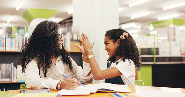 istock High five, education and teacher with child in library for studying, learning or tutoring at school. Happy, book and educator with girl student for celebration with correct answer at academy. 2252537910