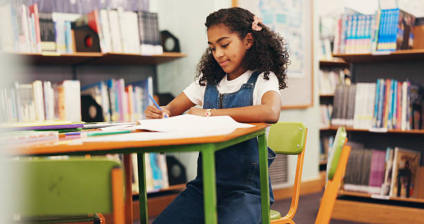 istock Library, learning and child with smile, writing or fine motor skills with knowledge, book and growth. Education, cognitive development and girl with assignment, paperwork and exam for scholarship 2252537964