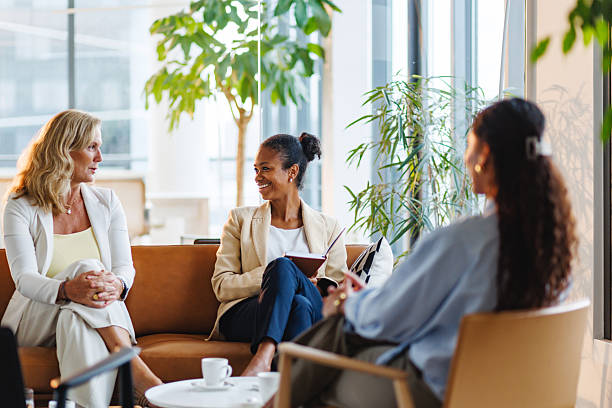 istock Joyful Businesswomen Engaging in Conversation in Bright Office 2252538423