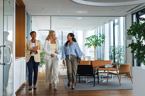 istock Professional Women Engaging in Lively Conversation While Walking at Office 2252538443
