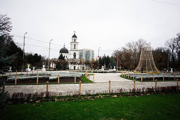 Chisinau, Moldova - November 22, 2025: A serene public park in Chisinau with a white church, circular paths, and festive light sculpture.