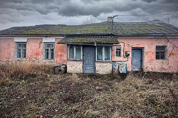 An abandoned one-story residential building, moss growth. Abandoned deserted house with dramatic sky