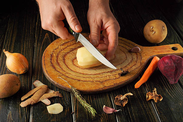 istock Hands skillfully chop a potato on a wooden cutting board surrounded by fresh vegetables and herbs in a cozy kitchen, creating a flavorful meal 2252556527