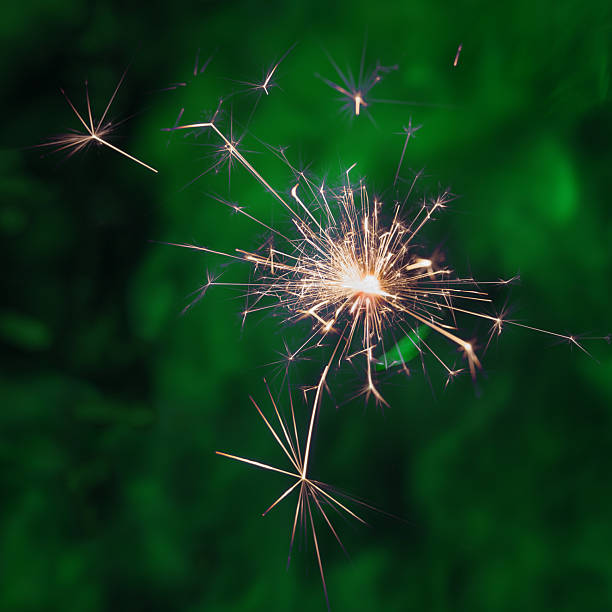 A vivid sparkler emits radiant sparks against a dark green backdropsymbol of festive light, motion, and celebration.