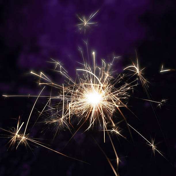 A sparkler bursts with golden light against a deep purple backgroundsymbol of celebration, motion, and festive warmth.