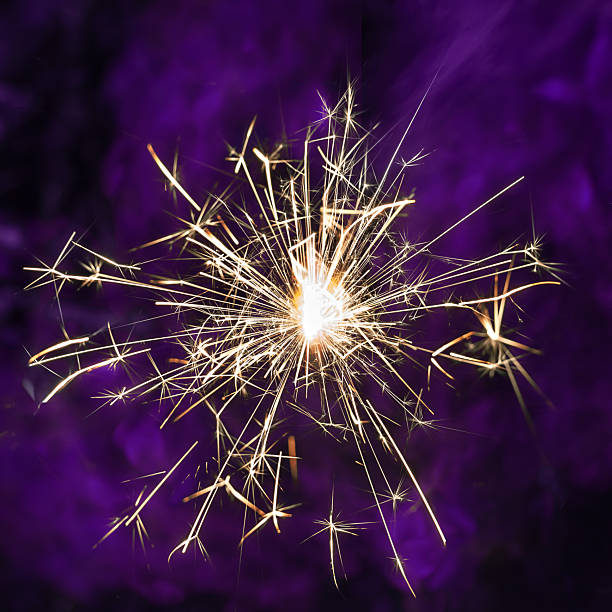 A sparkler bursts with golden light against a deep purple backgroundsymbol of celebration, motion, and festive warmth.