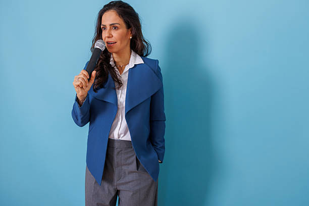 istock Woman speaking on microphone delivering speech, presenting information, public speaking, communication, and business presentation 2252559148