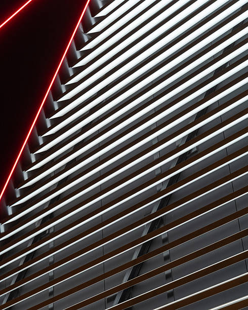 The geometric elegance of a contemporary building with horizontal blinds and vibrant red lighting. The contrast highlights the architectural features beautifully at night.