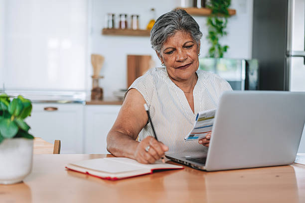 istock Senior Woman Writing Notes While Holding A Bill At Table 2252563278