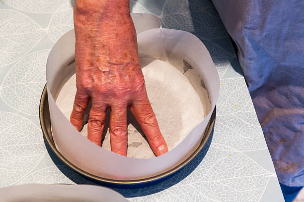 istock A mature female presses parchment paper into a baking tin for making a cheesecake on a table in a domestic kitchen 2252564375