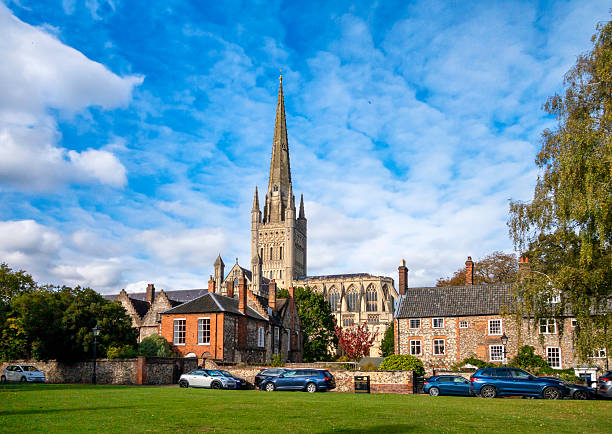 The lovely 11th century Norwich Cathedral seen behind houses in the Cathedral Close in the beautiful old city of Norwich in Norfolk, Eastern England on a sunny autumn day.