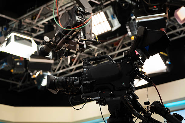 istock Television studio featuring a professional video camera on a tripod, a mounted jib crane, and bright studio lights rigged for broadcasting and media production 2252564612